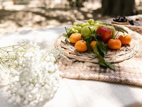 Obst auf einem sommerlich eingedeckten Tisch mit Blumen und Schattenspiel