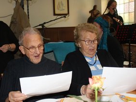 Zwei Vereinsmitglieder singen fröhlich bei einem Lied mit.